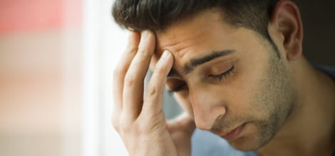 Image of young asian male holding head looking worried